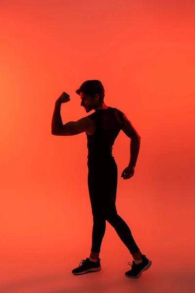 Athletic sportsman showing muscles on red background — Stock Photo