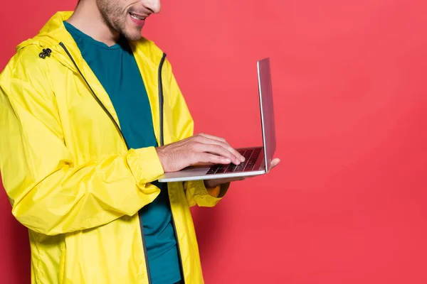 Vista recortada del deportista en chaqueta deportiva con ordenador portátil sobre fondo rojo - foto de stock