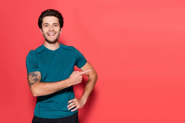 Positive sportsman pointing with finger on red background — Stock Photo