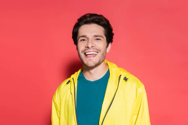 Positive sportsman in sports jacket looking at camera on red background — Foto stock