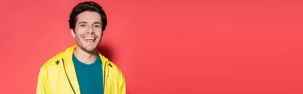 Brunette sportsman in sportswear looking at camera on red background, banner — Stockfoto