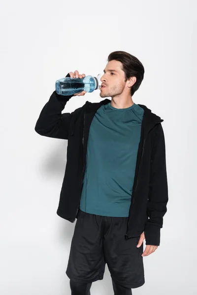 Sportsman en veste de sport eau potable sur fond gris — Photo de stock