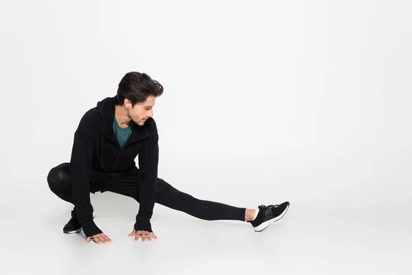 Brunette sportsman stretching on grey background — Stockfoto