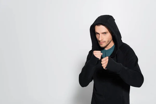 Combatiente en chaqueta deportiva mirando a la cámara sobre fondo gris - foto de stock