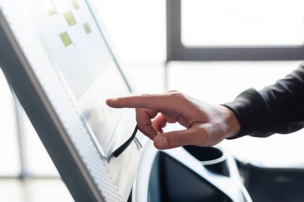 Cropped view of sportsman tuning treadmill in gym — Stock Photo