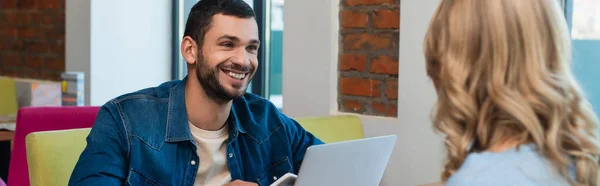 Smiling man looking at blurred blonde woman in restaurant, banner — Stockfoto