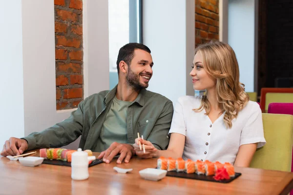 Fröhliches Paar schaut sich beim köstlichen Abendessen in der Sushi-Bar an — Stockfoto