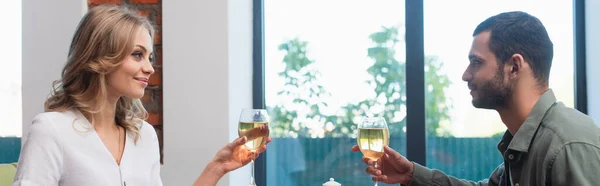 Jovem casal com copos de vinho branco olhando uns para os outros no restaurante, banner — Fotografia de Stock