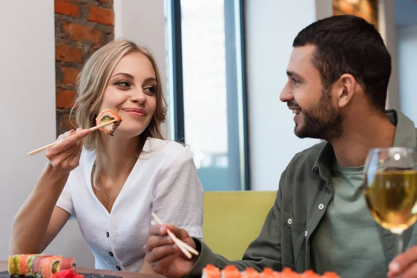 Cheerful couple looking at each other during dinner in sushi bar on blurred foreground — Foto stock