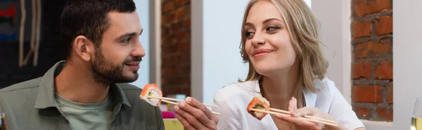 Щаслива пара дивиться один на одного під час їжі смачні суші-роли, банер — стокове фото