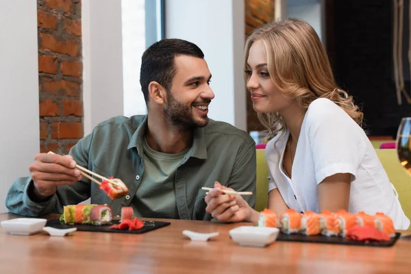 Happy man talking to blonde girlfriend during lunch in sushi bar — Foto stock