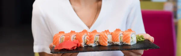 Vista recortada de la mujer con deliciosos rollos de sushi, pancarta - foto de stock