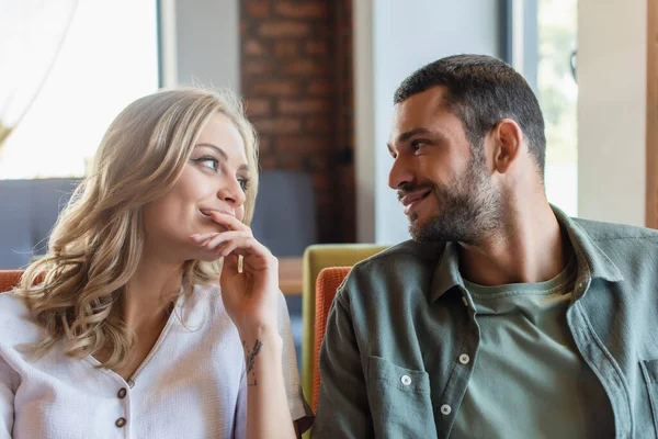 Pleased couple smiling at each other while sitting in cafe — Stockfoto