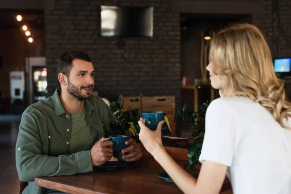 Young man talking to blurred girlfriend during date in cafe — Stock Photo