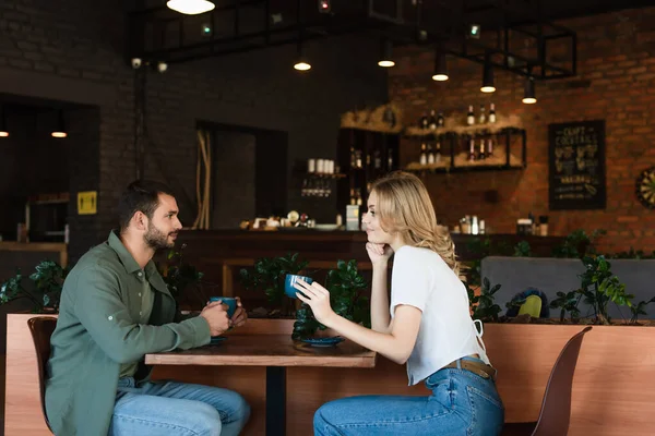 Side view of smiling woman looking at young man during date in cafe — Stockfoto