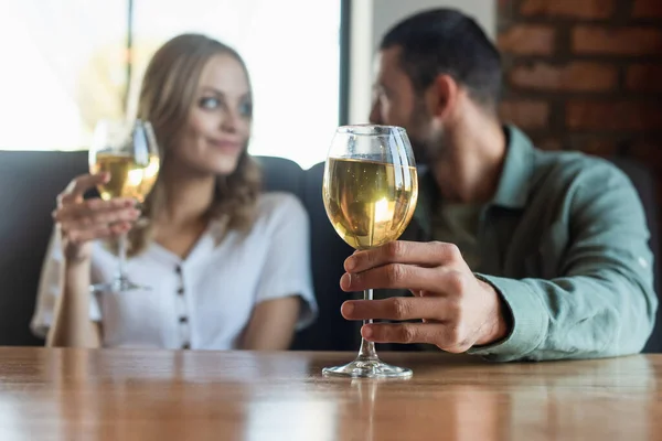 Foco selectivo de vidrio con vino blanco cerca de pareja que tiene cita romántica en la cafetería - foto de stock