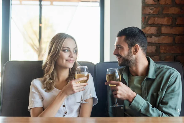 Felice giovane coppia con bicchieri di vino che si guardano mentre trascorrono del tempo in un caffè — Foto stock