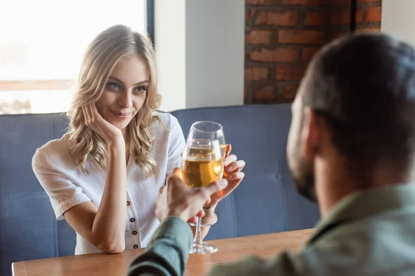 Heureux femme cliquetis verres à vin avec l'homme sur flou premier plan — Photo de stock