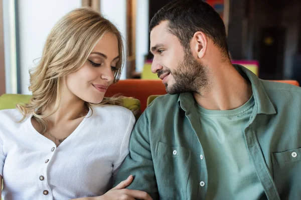 Young couple smiling while sitting together in restaurant — Stock Photo