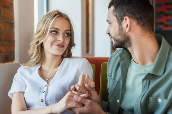 Glückliches junges Paar, das sich beim romantischen Date im Restaurant anschaut und Händchen hält — Stockfoto