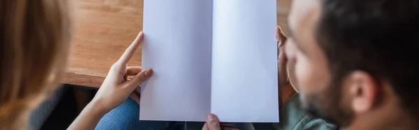 Частковий вид розмитого чоловіка і жінки з порожнім меню ресторану, банер — стокове фото