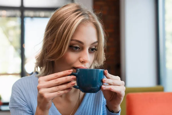 Bonita mujer rubia bebiendo café en restaurante - foto de stock