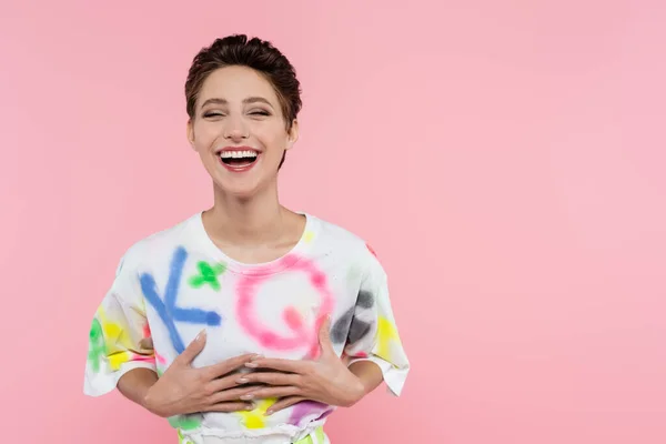 Aufgeregte brünette Frau lacht, während sie isoliert auf rosa Kamera schaut — Stockfoto