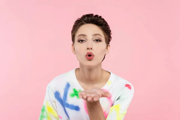 Stylish brunette woman blowing air kiss while looking at camera isolated on pink — Stock Photo