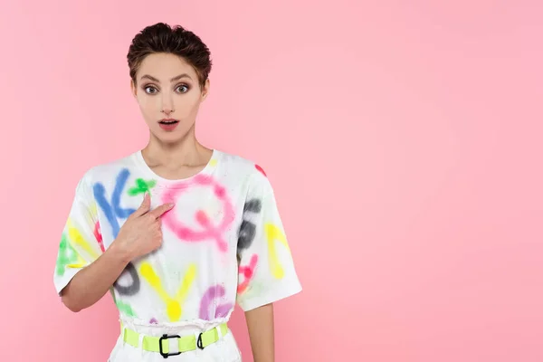 Entmutigte Frau in trendiger Freizeitkleidung, die auf sich selbst zeigt, während sie vereinzelt in rosa in die Kamera blickt — Stockfoto