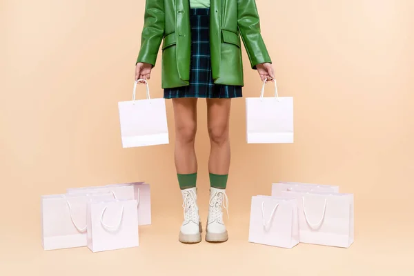 Partial view of woman in plaid skirt and white lace-up boots standing with purchases on beige — Fotografia de Stock