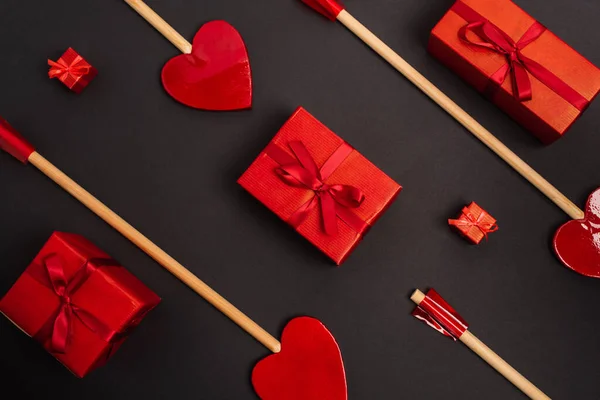 Top view of heart-shaped arrows near wrapped presents on black — Stock Photo