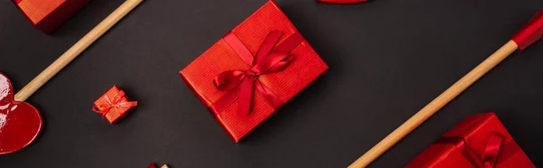 Vista superior de flechas de madera cerca de regalo envuelto aislado en negro, bandera - foto de stock