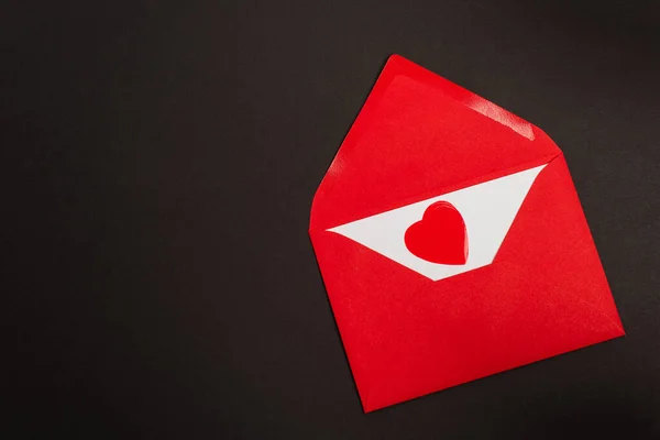 Vue du dessus de l'enveloppe rouge avec lettre d'amour et coeur coupé en papier isolé sur noir — Photo de stock