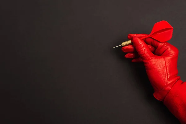 Vue recadrée de la femme en gant rouge tenant fléchettes sur noir — Photo de stock