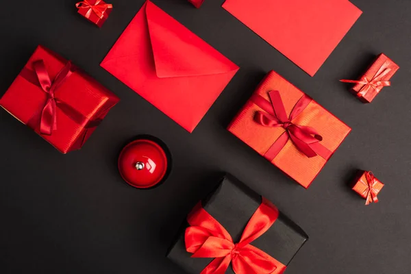 Top view of wrapped presents near metallic bell on black — Stockfoto