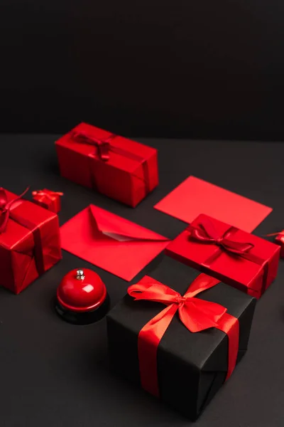 Wrapped presents and envelopes near metallic bell on black — Fotografia de Stock