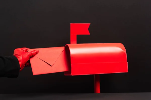 Cropped view of person in red glove putting envelope in post box on black — Fotografia de Stock