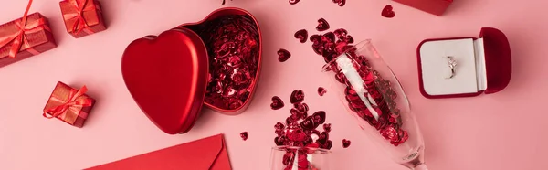 Top view of champagne glasses with shiny confetti near gift boxes, engagement ring and envelope on pink, banner — Fotografia de Stock