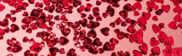 Vue du haut des cœurs de confettis rouges brillants sur rose, bannière — Photo de stock