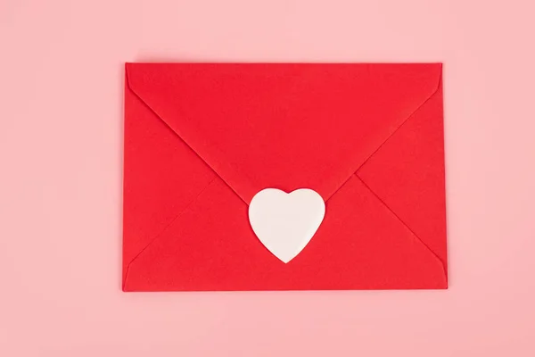 Top view of paper heart sticker on red envelope isolated on pink — Stockfoto