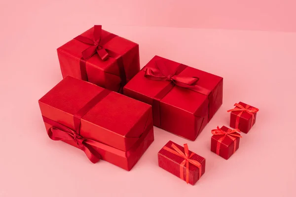 Rot verpackte Geschenkboxen mit Bändern auf rosa — Stockfoto