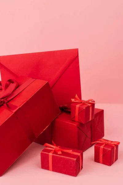 Red wrapped gift boxes and envelope on pink — Stock Photo