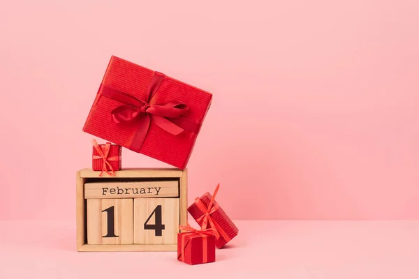 Caixas de presente vermelho no calendário de madeira com 14 fevereiro lettering em rosa — Fotografia de Stock