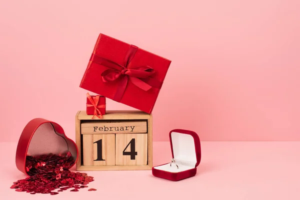 Rote Geschenkboxen auf Kalender mit 14 Februar nahe Verlobungsring und Konfetti auf rosa — Stockfoto