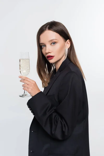 Young brunette woman with champagne glass looking at camera isolated on grey — Stock Photo