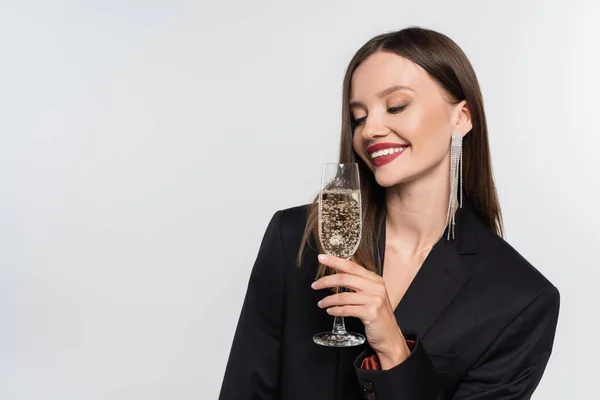 Happy young woman in black blazer holding glass of champagne isolated on grey — Stock Photo