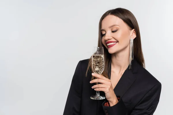 Feliz joven en blazer negro sosteniendo copa de champán aislado en gris — Stock Photo