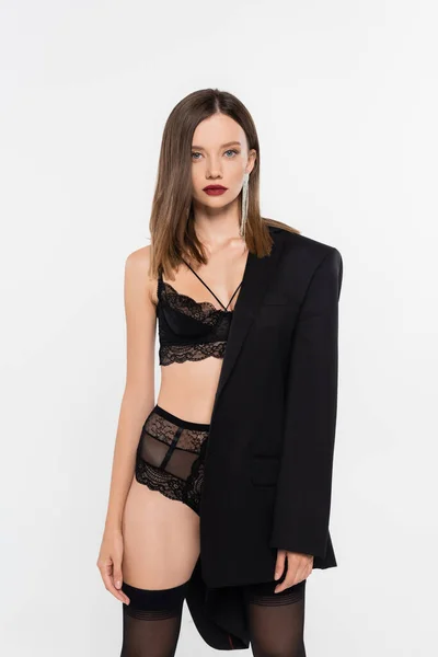 Femme sexy en dentelle noire sous-vêtements regardant la caméra tout en posant avec blazer noir isolé sur gris — Photo de stock