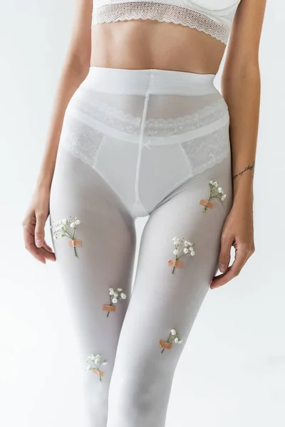 Vue partielle de femme sexy en soutien-gorge en dentelle, culotte et collants blancs avec de petites fleurs isolées sur gris — Photo de stock