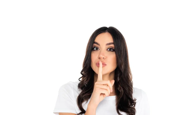 Young brunette woman showing hush sign while looking at camera isolated on white — стоковое фото